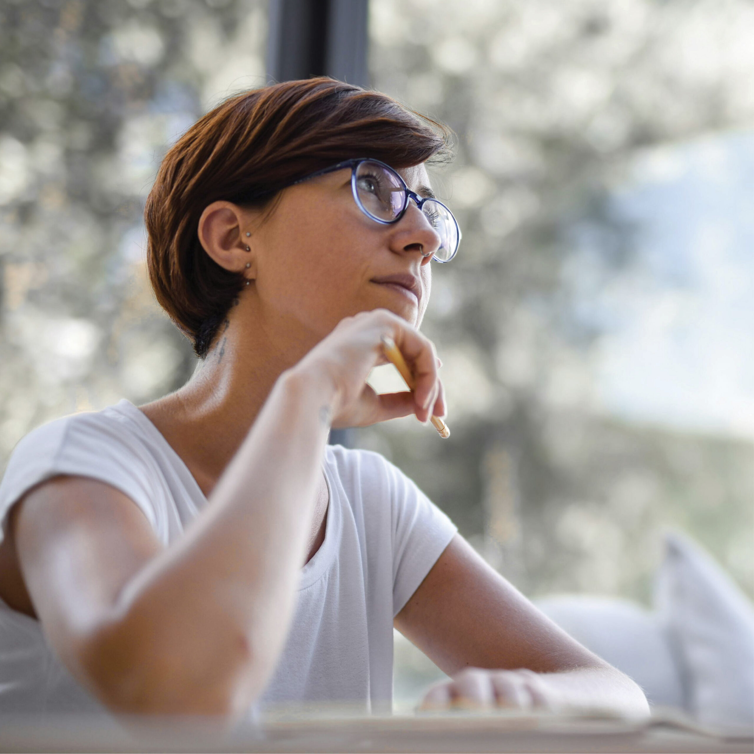 A woman in glasses looking contemplative.