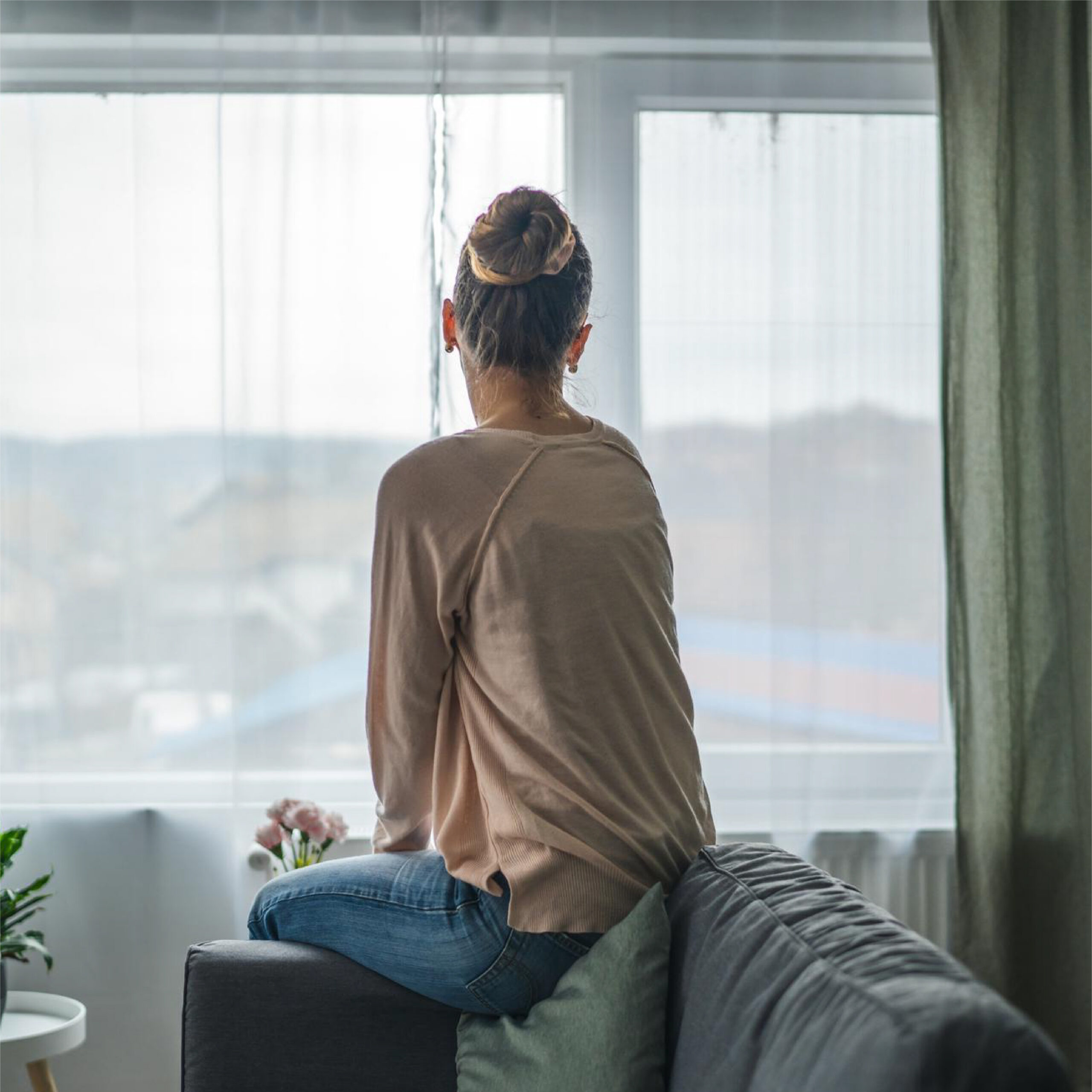 Woman sitting on a couch looking out a window contemplating divorce communication