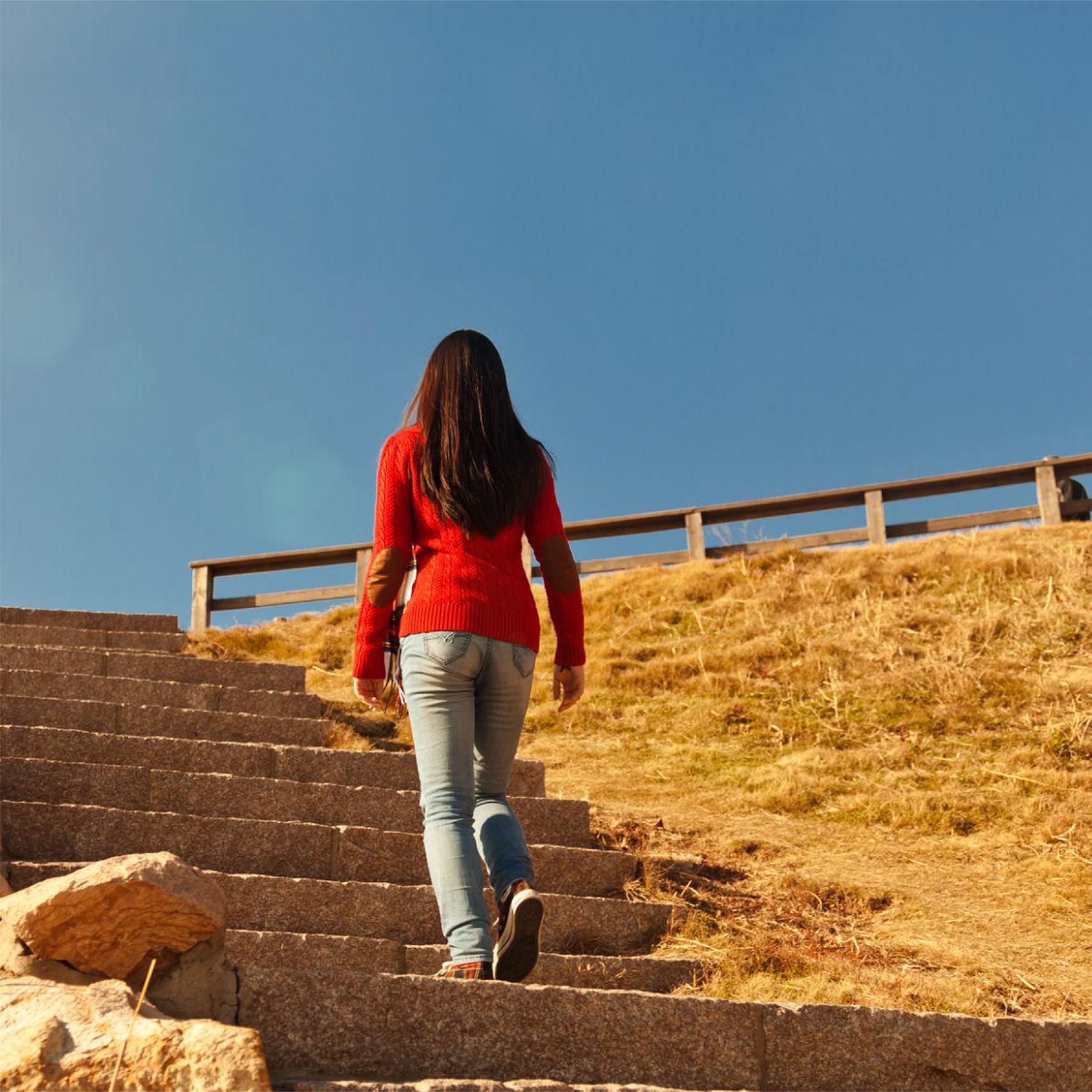 Woman taking one small step at a time up a set of stairs.